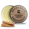 Sandalwood beard balm tin with lid open, two wood pieces beside.